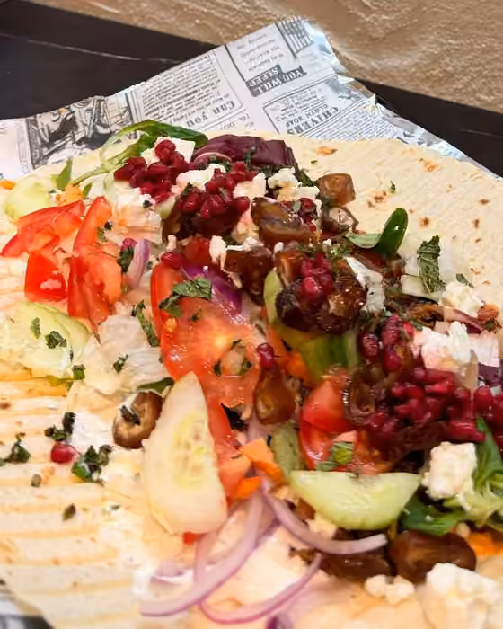 Dürüm abierto con verduras, granada, dátiles y queso feta